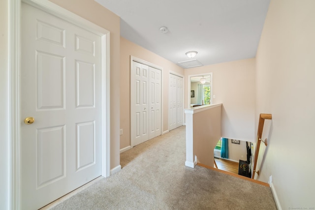 hall with an upstairs landing, carpet flooring, and baseboards