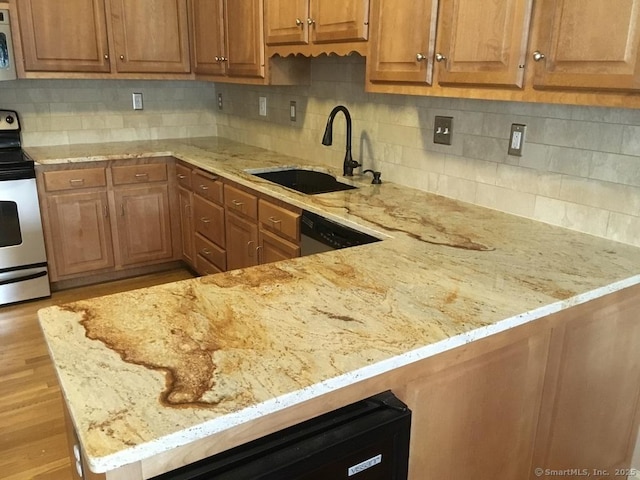 kitchen with a sink, appliances with stainless steel finishes, light stone countertops, and backsplash