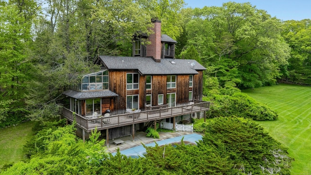 32 Beeholm Rd, Redding, CT 06896 - rear view of property featuring a chimney, a deck, a sunroom, a shingled roof, and a forest view