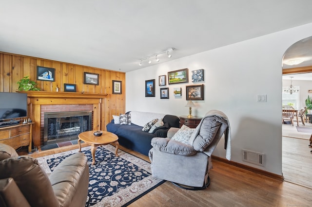 149 Edgewood Dr, Torrington, CT 06790 - living area with arched walkways, wood finished floors, wooden walls, a chandelier, and a brick fireplace