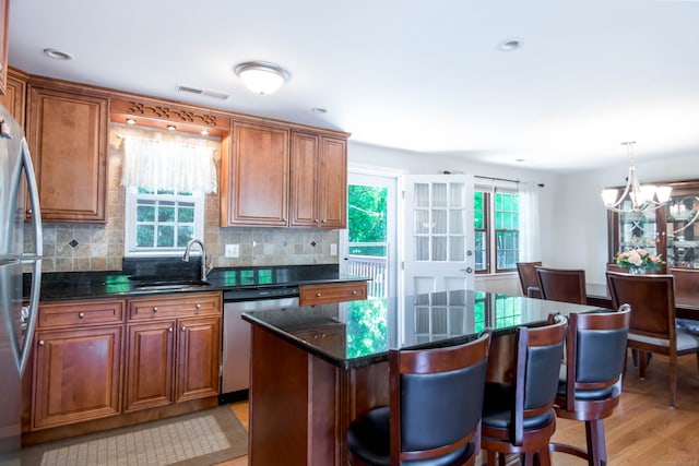 27 Lansing Ave, Trumbull, CT 06611 - kitchen with appliances with stainless steel finishes, a sink, a kitchen breakfast bar, a chandelier, and decorative backsplash