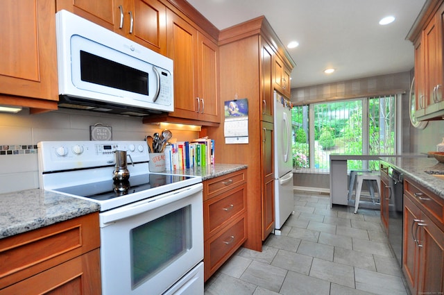 5 Spyglass Dr Unit 5, Avon, CT 06001 - kitchen with white appliances, brown cabinetry, tasteful backsplash, light stone counters, and recessed lighting