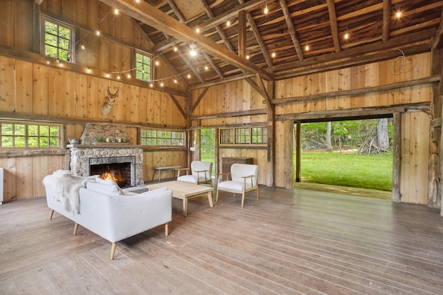 336 Old Branchville Rd, Ridgefield, CT 06877 - living area with high vaulted ceiling, a stone fireplace, wood walls, healthy amount of natural light, and wood-type flooring