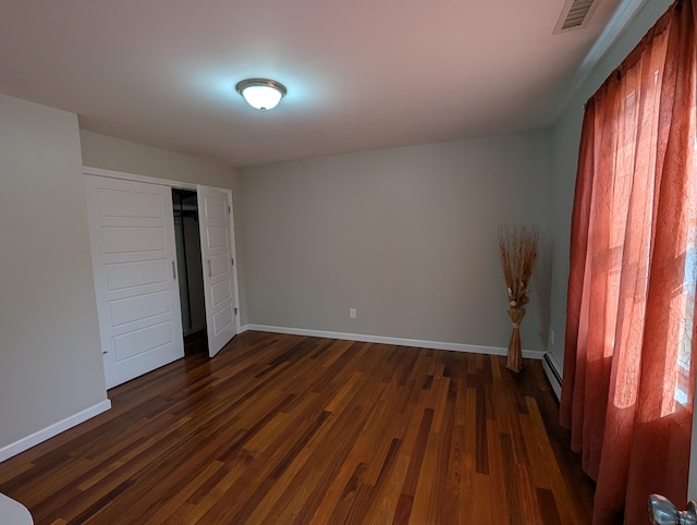 9 Washington Rd, Windsor, CT 06095 - unfurnished bedroom featuring dark wood-style flooring, baseboards, a baseboard heating unit, and a closet