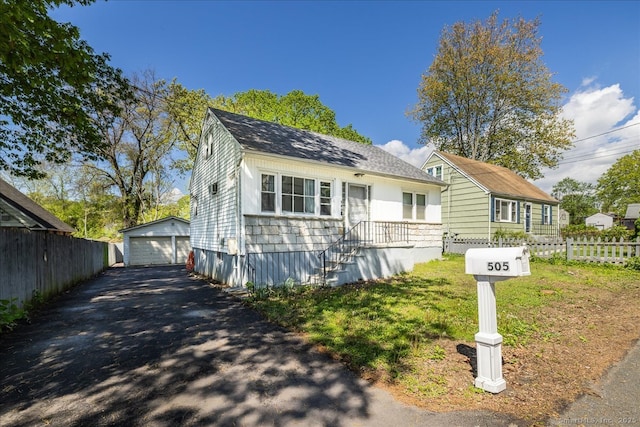 view of front of home with fence, a garage, an outbuilding, and a shingled roof