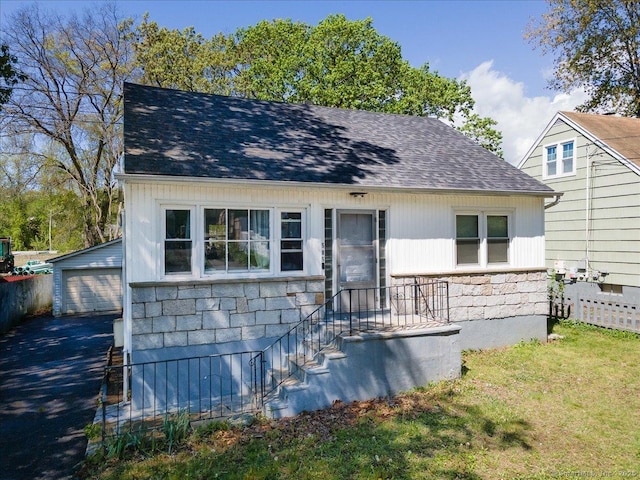 view of front of property with stone siding, an outbuilding, roof with shingles, and a garage