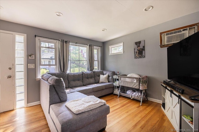living room with baseboards, light wood-style floors, a wall unit AC, and recessed lighting