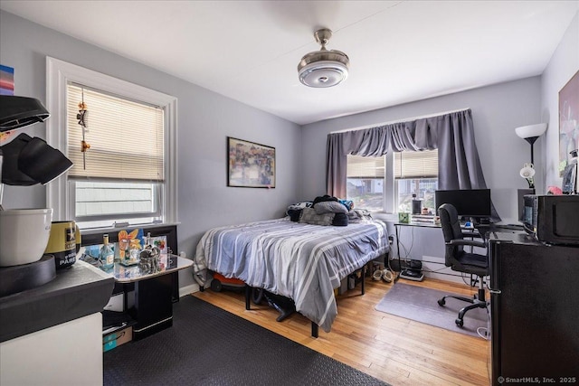 bedroom with wood finished floors and an office area