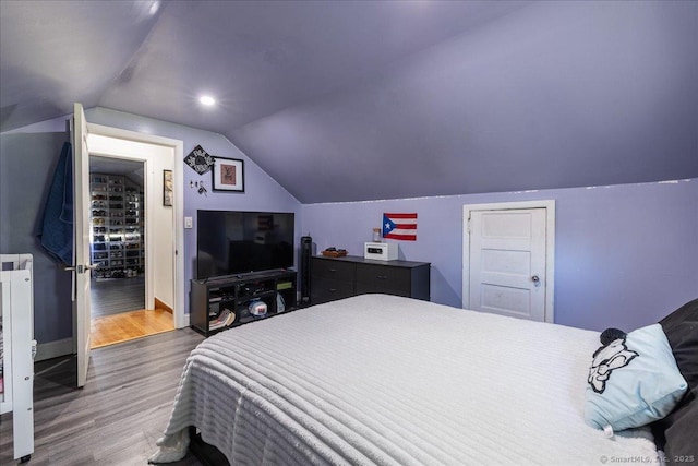 bedroom featuring wood finished floors, lofted ceiling, and baseboards