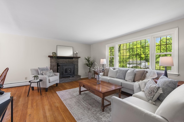 27 Scudder Rd, Newtown, CT 06470 - living room featuring baseboards, light wood finished floors, a stone fireplace, and a baseboard radiator