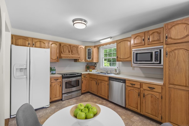 27 Scudder Rd, Newtown, CT 06470 - kitchen with stainless steel appliances, a sink, light countertops, and brown cabinetry