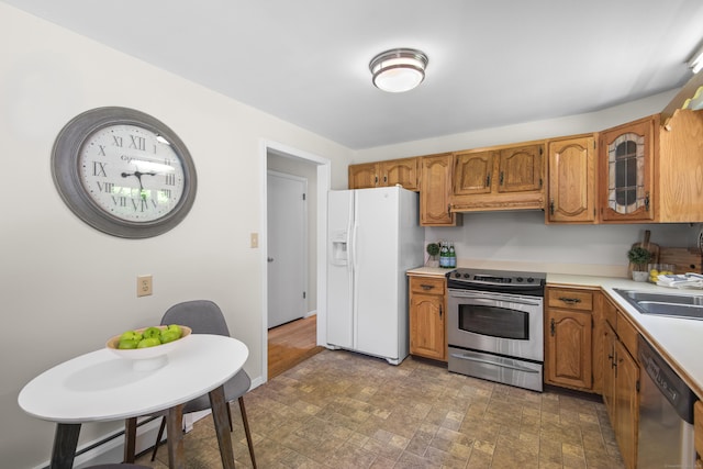 27 Scudder Rd, Newtown, CT 06470 - kitchen with stainless steel appliances, light countertops, brown cabinets, glass insert cabinets, and a sink