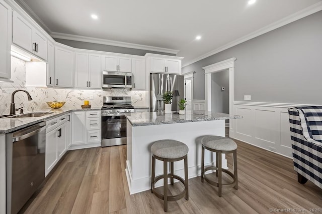 210 Munson Rd Unit 3-C, Wolcott, CT 06716 - kitchen with stainless steel appliances, ornamental molding, a center island, white cabinets, and wainscoting