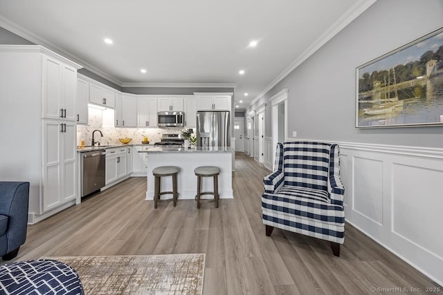 210 Munson Rd Unit 3-C, Wolcott, CT 06716 - kitchen with appliances with stainless steel finishes, crown molding, white cabinetry, a center island, and light wood-style floors