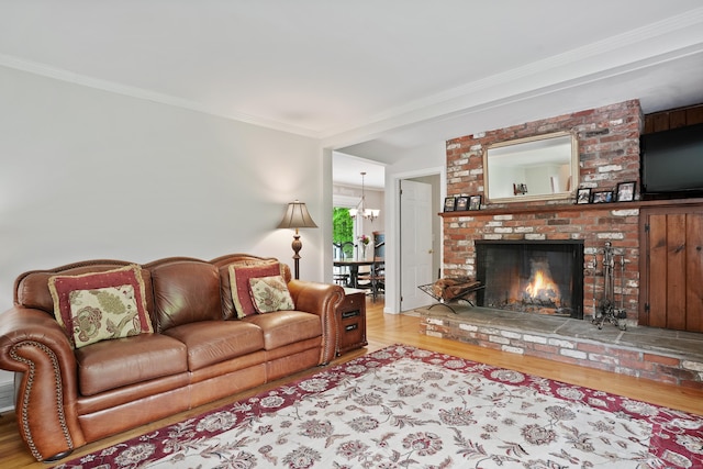 living area with wood finished floors, crown molding, a fireplace, and a chandelier