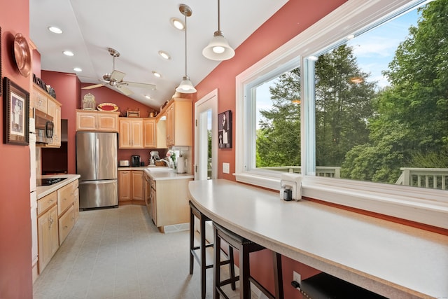kitchen featuring appliances with stainless steel finishes, light brown cabinets, lofted ceiling, ceiling fan, and hanging light fixtures