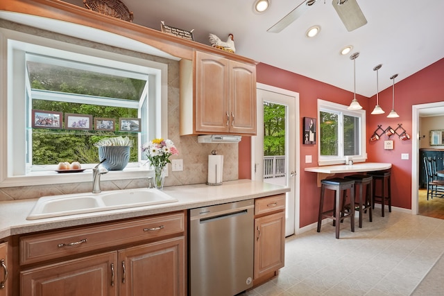 kitchen featuring dishwasher, a sink, vaulted ceiling, light countertops, and hanging light fixtures