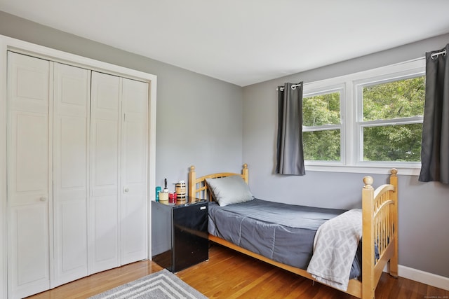 bedroom with wood finished floors, a closet, and baseboards