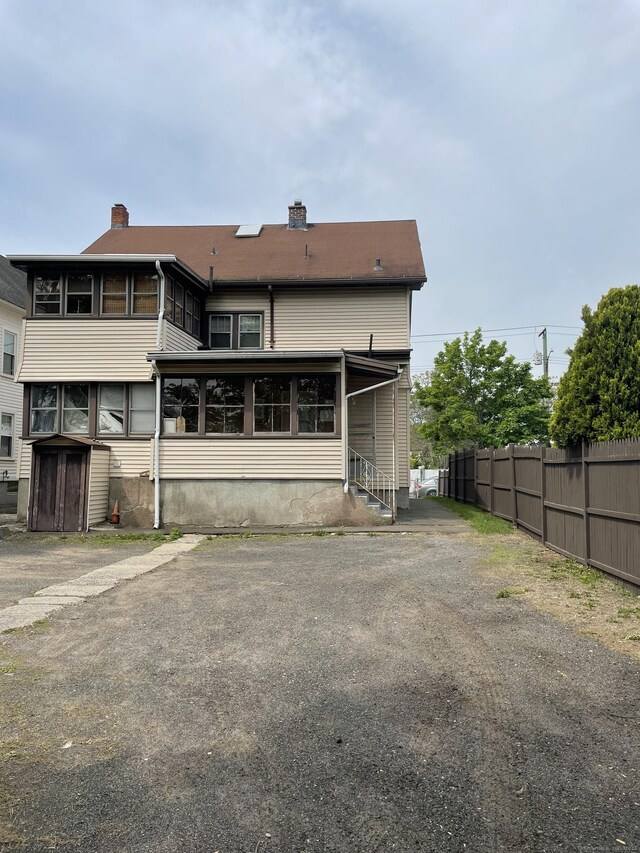 339 Washington Ave, West Haven, CT 06516 - back of property with fence, a storage unit, a chimney, an outbuilding, and a sunroom