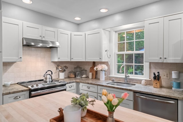 57 Elm Ridge Rd, Stonington, CT 06379 - kitchen featuring appliances with stainless steel finishes, under cabinet range hood, tasteful backsplash, white cabinets, and light stone countertops