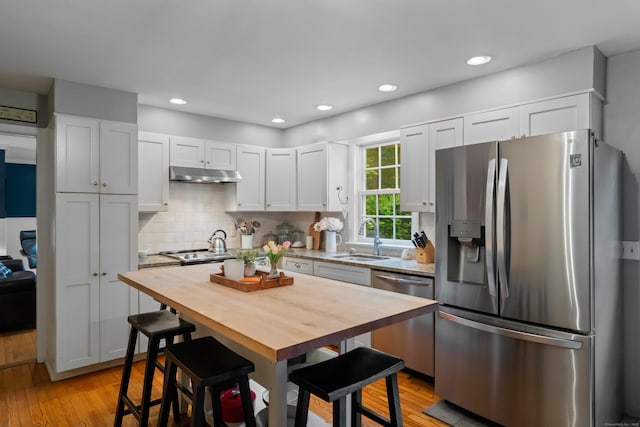 57 Elm Ridge Rd, Stonington, CT 06379 - kitchen with appliances with stainless steel finishes, under cabinet range hood, light wood-type flooring, backsplash, and white cabinets
