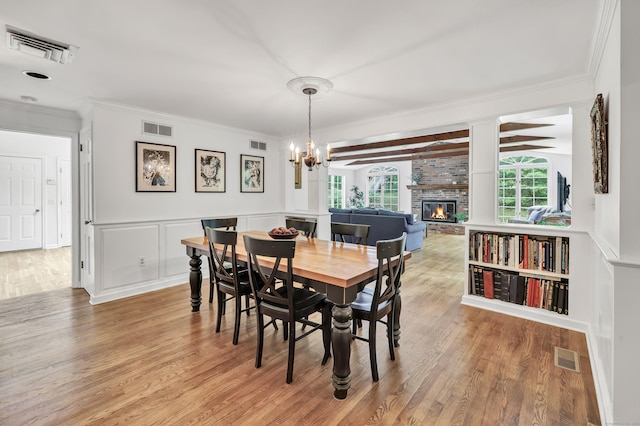 73 Golden Hill St, Trumbull, CT 06611 - dining space featuring light wood finished floors, a fireplace, ornamental molding, a chandelier, and wainscoting