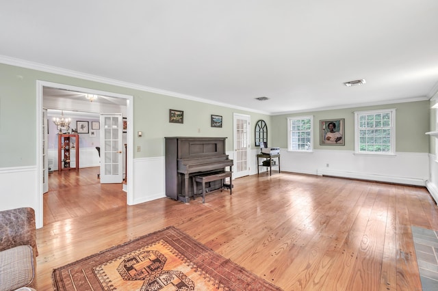 73 Golden Hill St, Trumbull, CT 06611 - living area featuring light wood-type flooring, a baseboard heating unit, ornamental molding, a chandelier, and a wainscoted wall