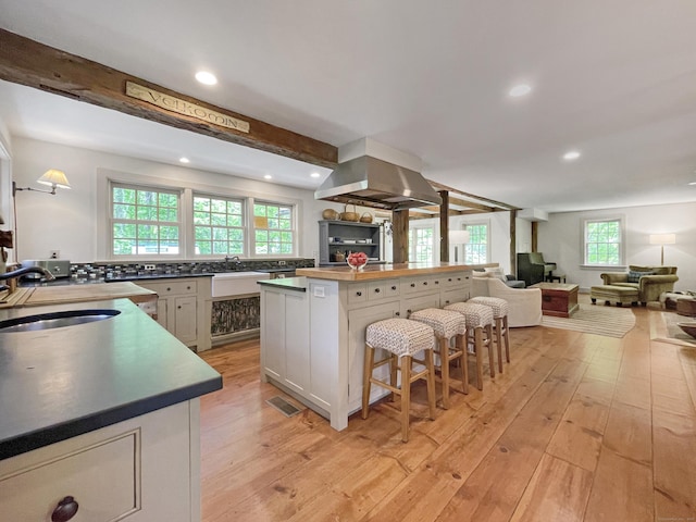 114 Ruscoe Rd, Wilton, CT 06897 - kitchen with a sink, island exhaust hood, a breakfast bar area, light wood-style flooring, and plenty of natural light