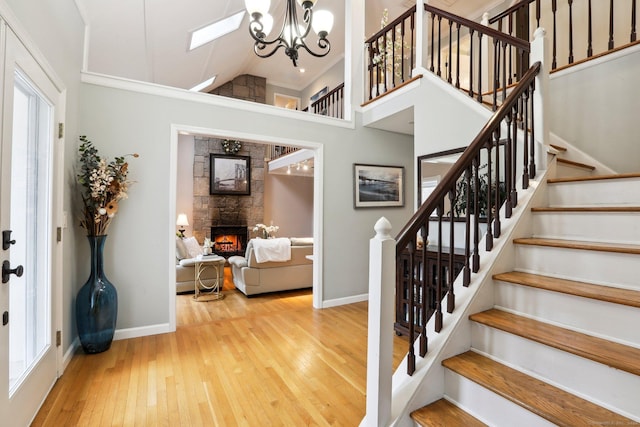 8 Grants Ln, New Milford, CT 06776 - stairway with a stone fireplace, hardwood / wood-style floors, baseboards, a chandelier, and high vaulted ceiling