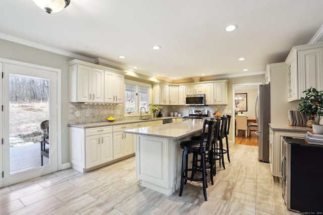 8 Grants Ln, New Milford, CT 06776 - kitchen with appliances with stainless steel finishes, a center island, light stone countertops, ornamental molding, and a kitchen bar