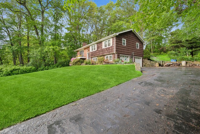 14 Button Rd, Shelton, CT 06484 - view of front of home with a chimney, driveway, an attached garage, and a front lawn