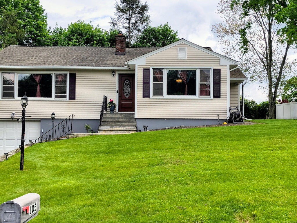 view of front of home featuring an attached garage, a chimney, a front yard, and entry steps