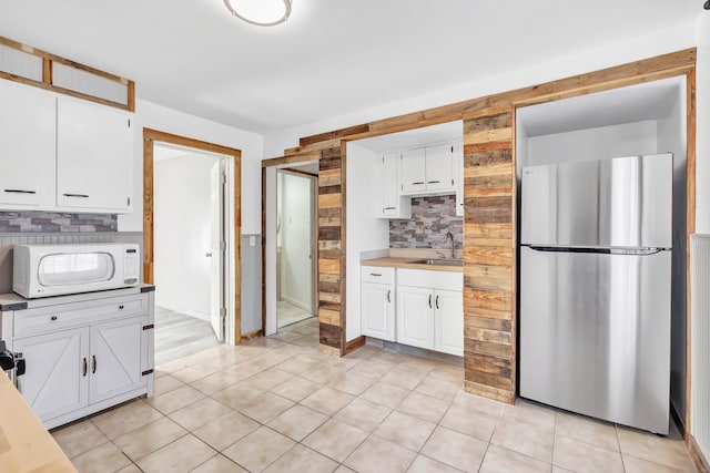 56 Gem Ave, Bridgeport, CT 06606 - kitchen featuring freestanding refrigerator, white microwave, backsplash, a sink, and white cabinets