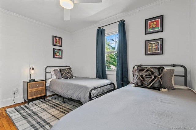 bedroom featuring ornamental molding, wood finished floors, baseboards, and a ceiling fan