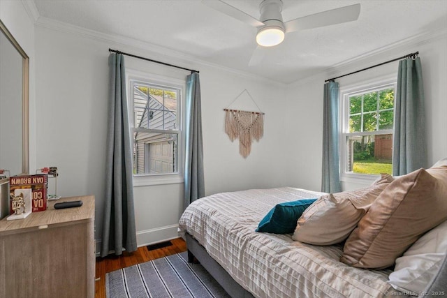 bedroom with wood finished floors, crown molding, baseboards, and ceiling fan
