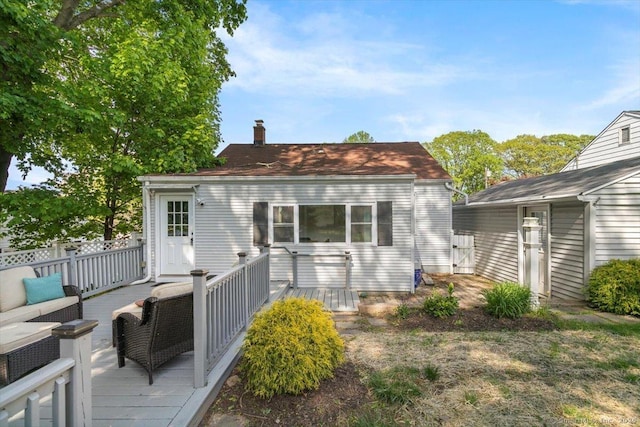 back of property featuring a deck, an outdoor living space, and a chimney