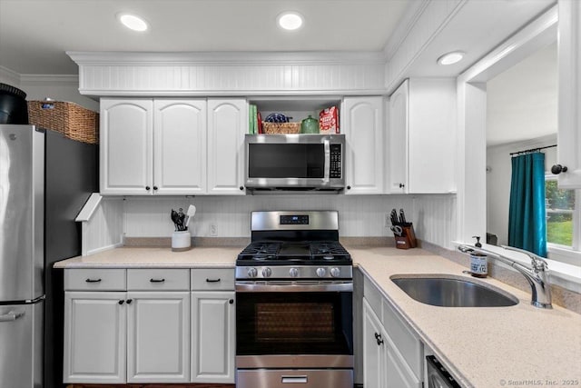 kitchen featuring appliances with stainless steel finishes, a sink, white cabinets, light countertops, and recessed lighting