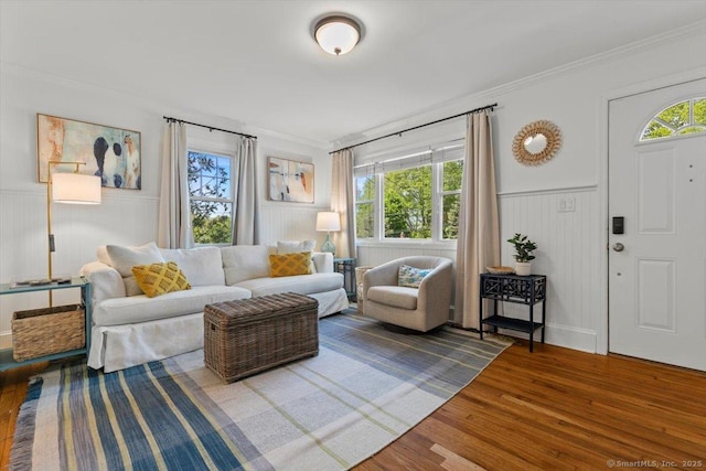 living room with wood finished floors, wainscoting, and crown molding