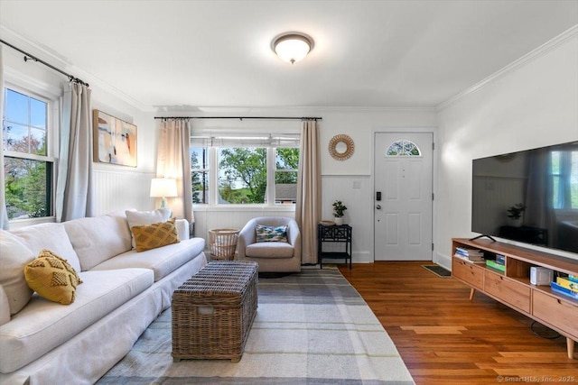 living room with crown molding, wood finished floors, and a wainscoted wall