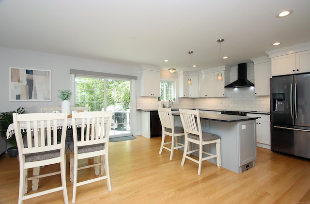 229 Long Hill Cross Rd, Shelton, CT 06484 - kitchen featuring stainless steel refrigerator with ice dispenser, wall chimney exhaust hood, a center island, light wood-style flooring, and a kitchen breakfast bar