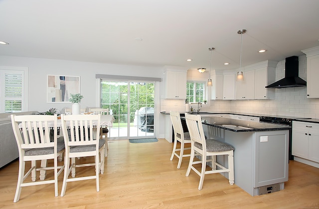 229 Long Hill Cross Rd, Shelton, CT 06484 - kitchen with wall chimney exhaust hood, a center island, a kitchen breakfast bar, light wood finished floors, and white cabinetry