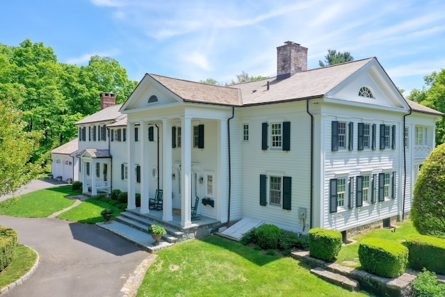1191 Oenoke Rdg, New Canaan, CT 06840 - neoclassical / greek revival house featuring a chimney, asphalt driveway, and a front yard