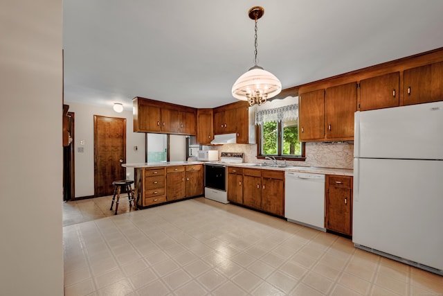 kitchen with white appliances, a sink, light countertops, under cabinet range hood, and brown cabinetry