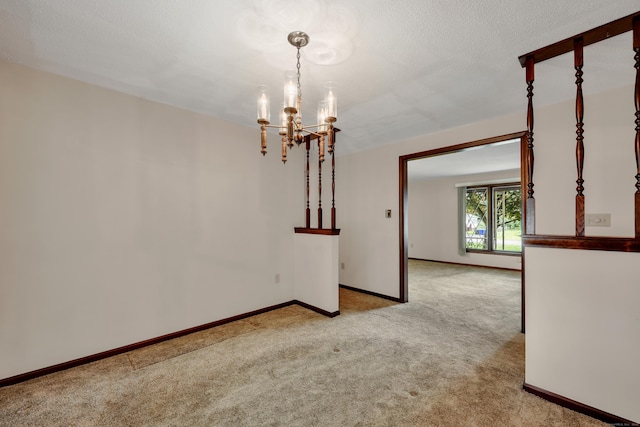 spare room with a chandelier, light carpet, and baseboards