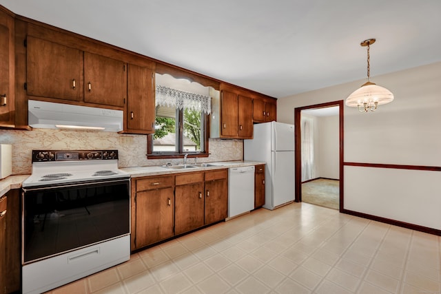 kitchen with white appliances, under cabinet range hood, a sink, and light countertops