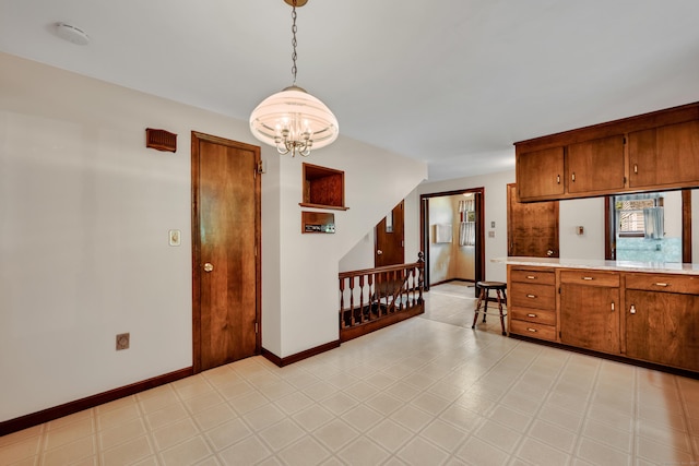 kitchen with a chandelier, brown cabinets, and baseboards