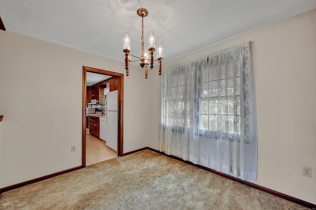 empty room featuring light carpet, a chandelier, and baseboards