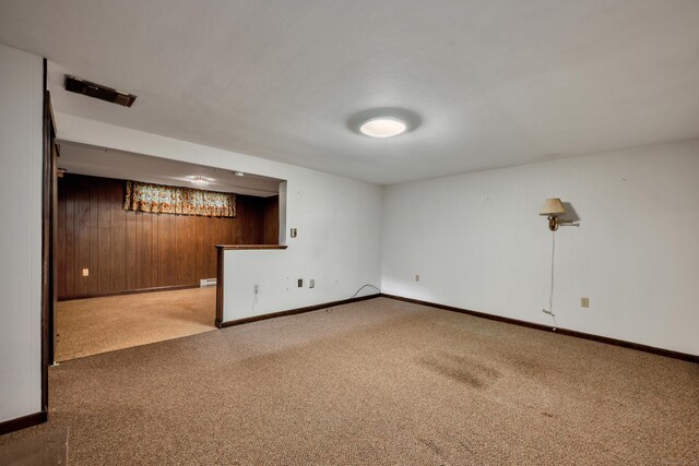 finished below grade area with carpet flooring, baseboards, and wood walls