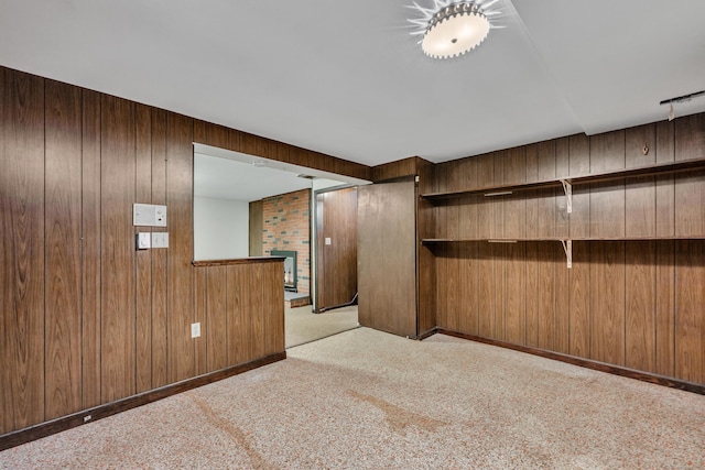 unfurnished room featuring wood walls and light colored carpet