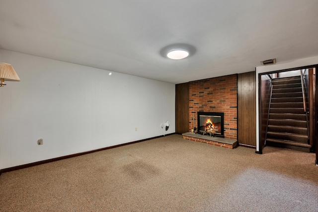 unfurnished living room featuring a brick fireplace, stairs, carpet floors, and baseboards